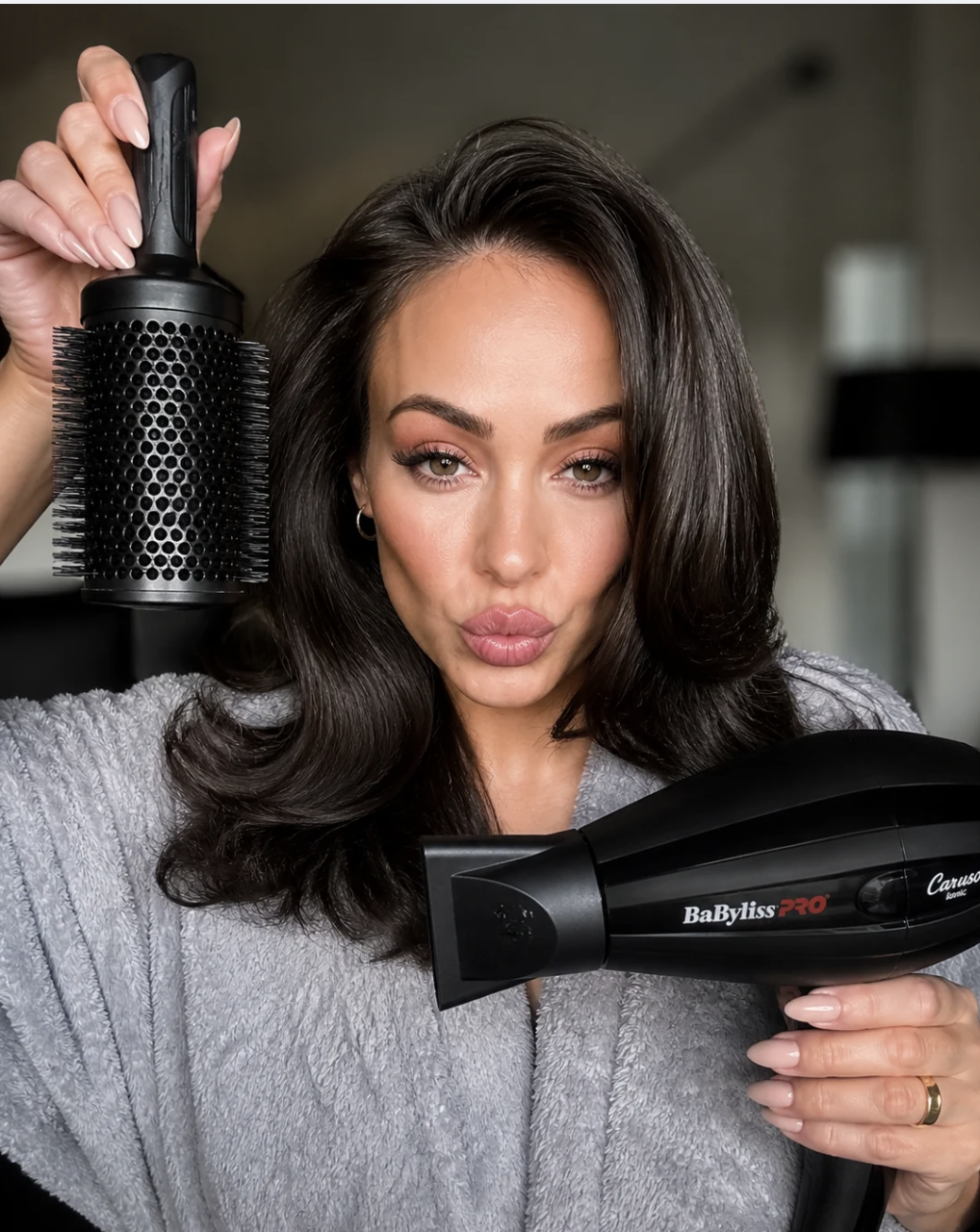 Tay segurando escova redonda e secador BaByliss Pro
